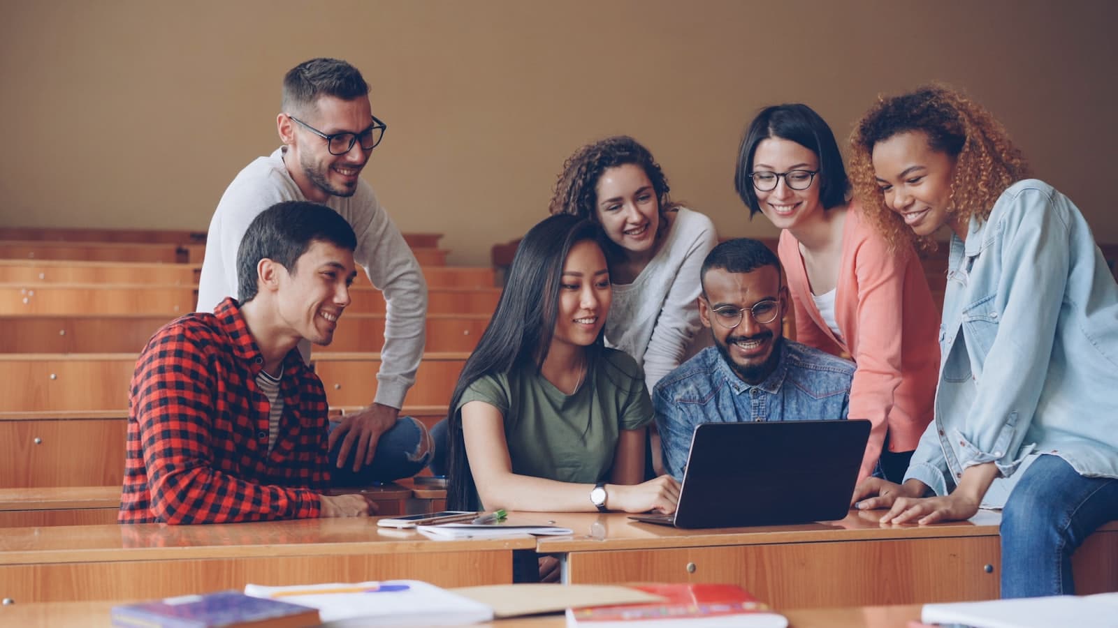 A diverse group of students collaborating around a laptop