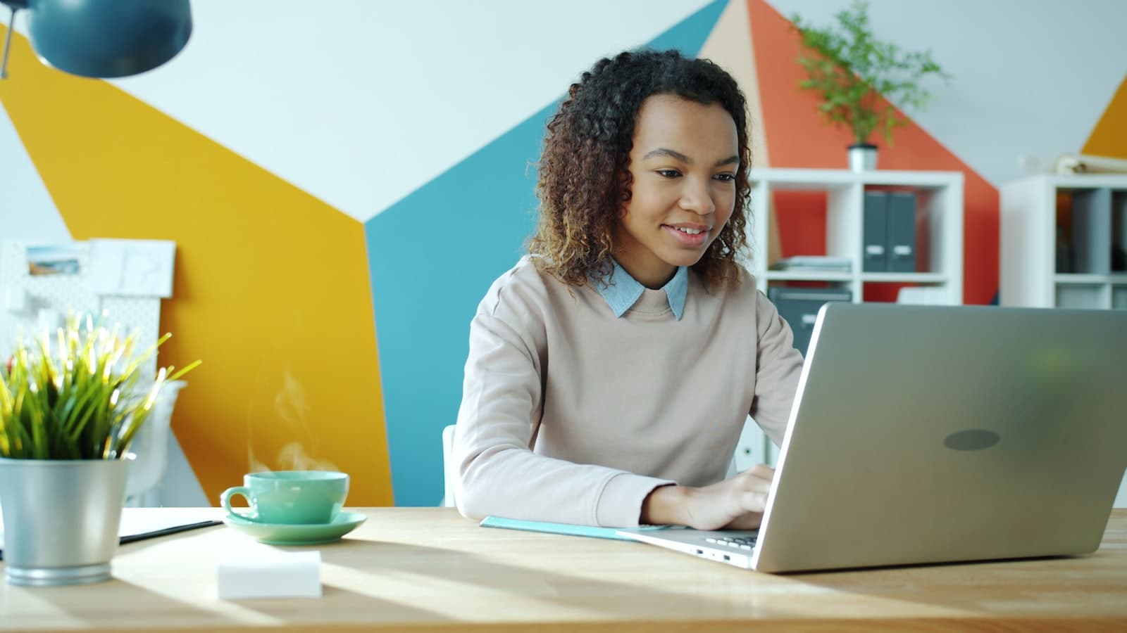 A student working focused on a laptop at a bright desk