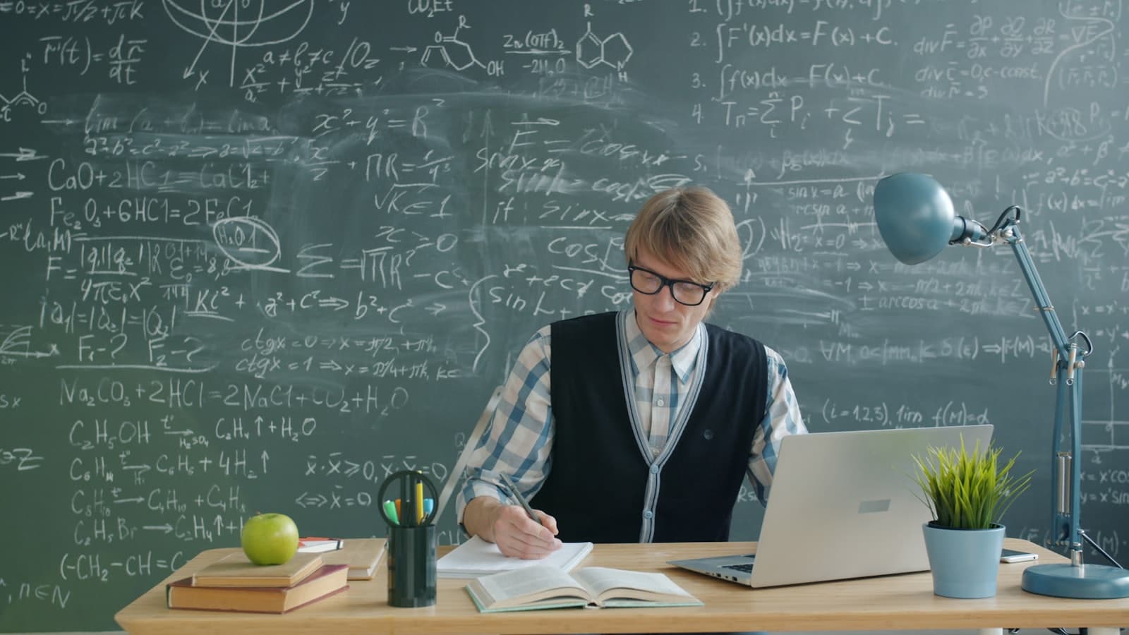 A student studying at a desk with a laptop and notes