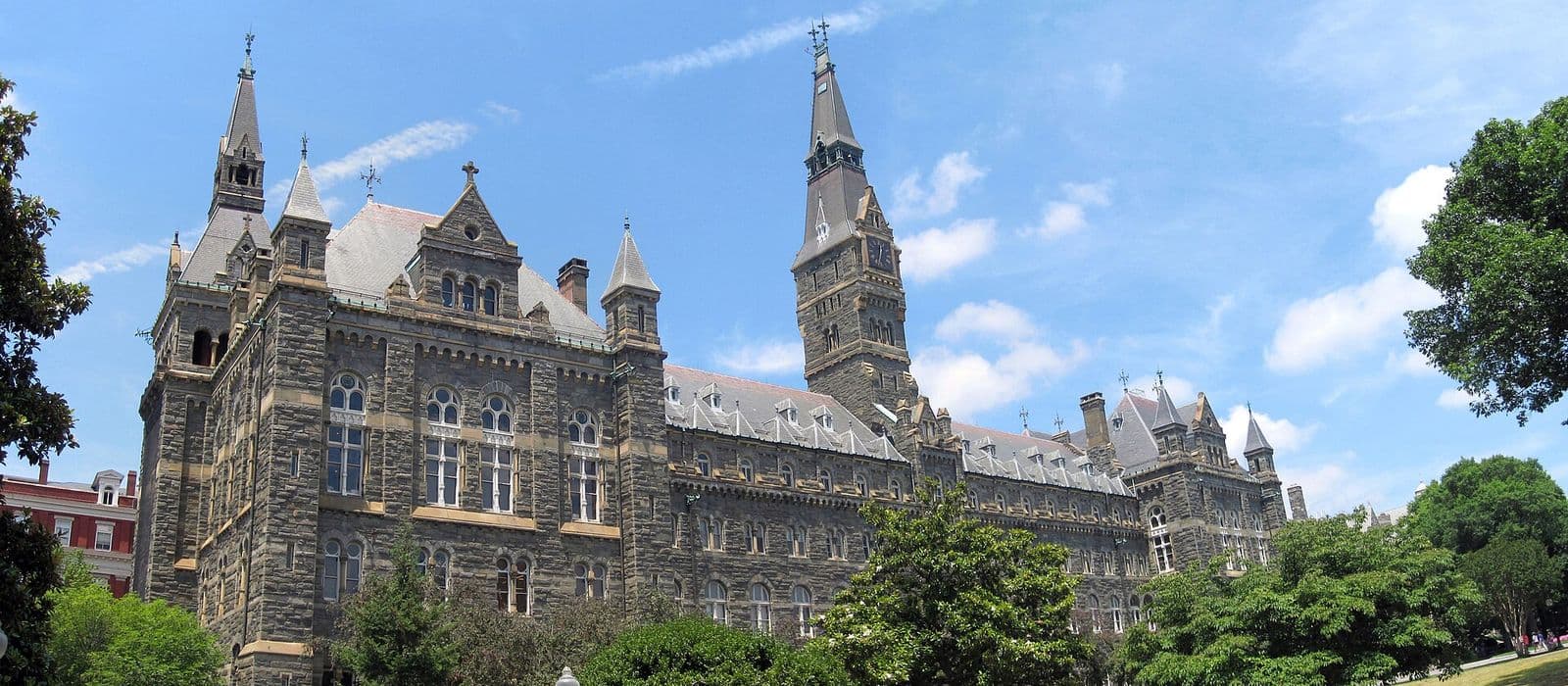 A historic university hall with spires and a clock tower on a sunny day